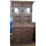 A 19th century carved oak glazed cabinet on base, the upper section with two glazed doors