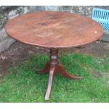 An Antique oak tripod table, the circular tilt top raised on a turned column with three outswept