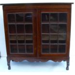 A 19th century rosewood two door glazed bookcase, with shaped apron and raised on short cabriole