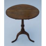 A 19th century oak tripod table, the circular tilt top raised on a turned column with three outswept