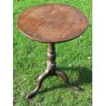 An Antique oak tripod table, the circular top raised on a turned column with three outswept