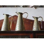 A Graduated Set of Three Brass Jugs with crocodile skin patination