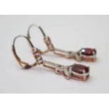 Sterling Silver and Rose Gold Plated Garnet and Diamond drop earrings featuring, 2 oval cut, dark