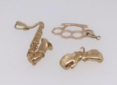 Three 9ct gold charms comprising a saxophone, a pair of boxing gloves and a knuckle duster, total