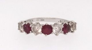 An 18ct white gold ruby and diamond seven stone ring set with three round brilliant cut rubies,