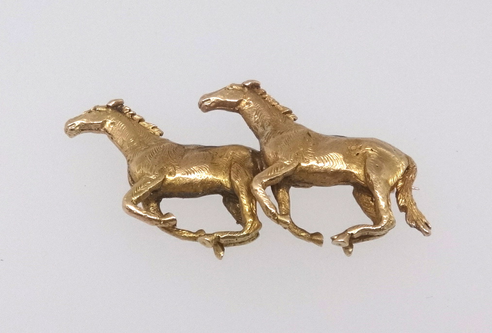 A 9ct gold brooch modelled as a pair of galloping horses, marked 'A & W', length 50mm, approx 18.