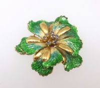 An 18ct brooch modelled as a flower head with green enamelled leaves set with sapphires, diameter