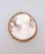 An antique cameo brooch with a portrait of a lady with a bird and flowing hair in a yellow metal