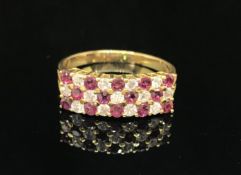 An 18ct ruby and diamond ring set with three rows of alternate stones, size N.