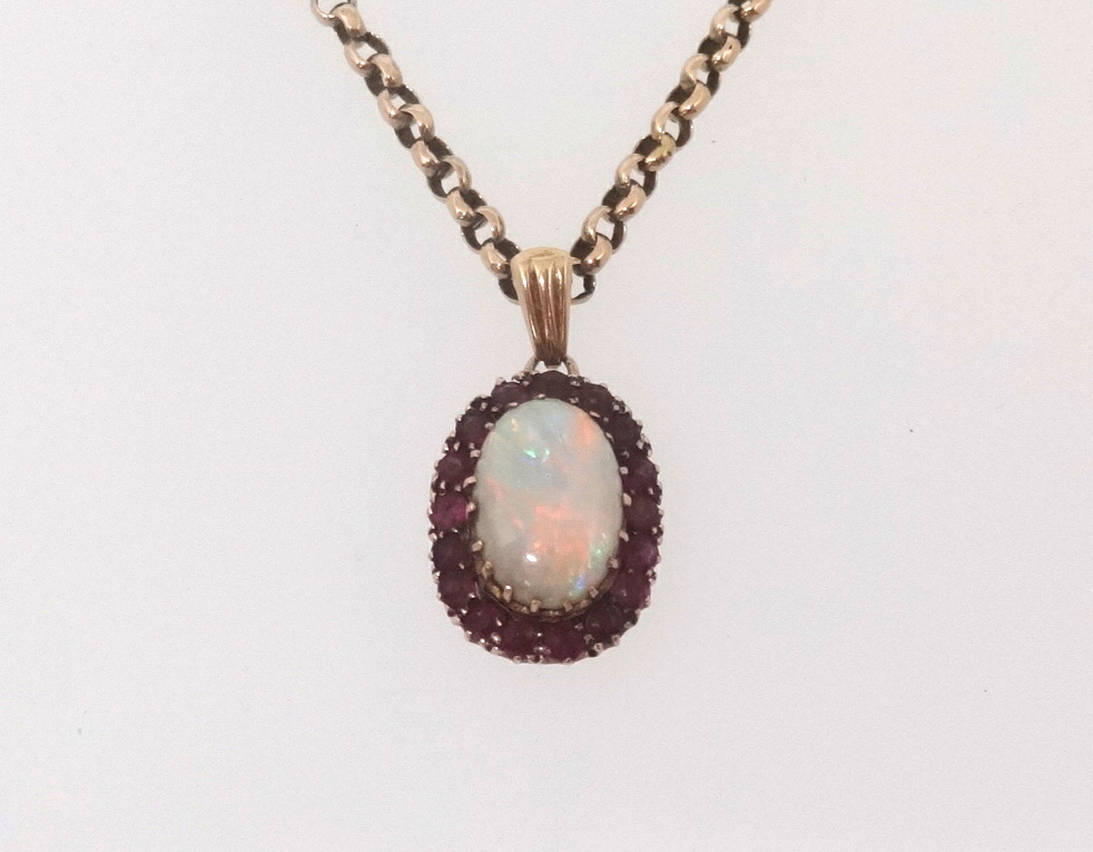 A ruby and opal cluster pendant set on a yellow metal chain, unmarked.