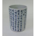 An Oriental porcelain brush pot decorated in blue and white with script, height 16cm.