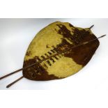 An African cow hide shield and a hunting spear, length of shield approx 135cm.