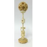 An antique carved ivory puzzle ball on carved figure stand, height 25cm with original box.