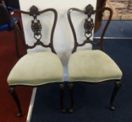 A pair of Edwardian carved mahogany bedroom chairs.