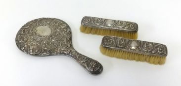 A three piece silver back dressing table set comprising hand mirror and two brushes.