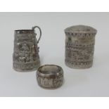 A foreign silver small tobacco jar decorated with an eastern town scene, together with a similar