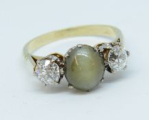 A three stone ring, set in unmarked yellow gold, the centre stone possibly 'Chrysoberyl'. size L.