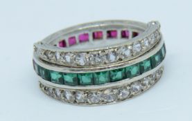 A white gold reverse ring set with channels of emeralds and rubies and diamond effect stones,