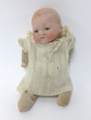 Armand Marseille, bisque head baby doll with open and close eyes and fabric body, height 25cm.