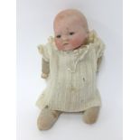 Armand Marseille, bisque head baby doll with open and close eyes and fabric body, height 25cm.