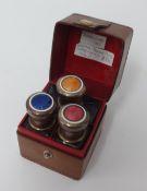 Travelling set containing three enamelled top scent bottles in leather case.
