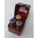 Travelling set containing three enamelled top scent bottles in leather case.