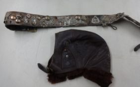 An old leather belt mounted with various military cap badges including regimental cap badges