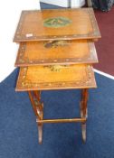 An Edwardian satinwood nest of three tables, the tops each painted with musical instruments on