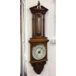 A late Victorian aneroid barometer in a large carved oak case set with a thermometer, height 125cm.