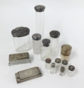 A collection of silver topped toilet jars and a silver rectangular match striker.