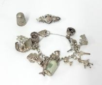 A silver charm bracelet (58.80gms), thimble and brooch (3).