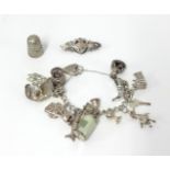 A silver charm bracelet (58.80gms), thimble and brooch (3).