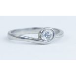A platinum and diamond solitaire ring set with a round brilliant cut diamond with a rub over setting