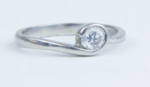 A platinum and diamond solitaire ring set with a round brilliant cut diamond with a rub over setting