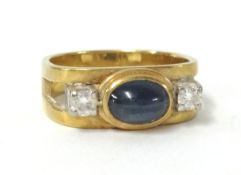 A poulson cabochon sapphire and diamond three stone ring, size K.