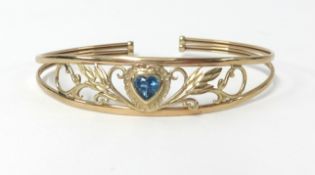 A 9ct gold torque style bangle with blue topaz heart centre stone, weight approx 6.4gms.