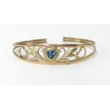 A 9ct gold torque style bangle with blue topaz heart centre stone, weight approx 6.4gms.