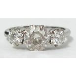 A platinum three stone diamond ring set with round brilliant cut diamonds, the centre diamond approx