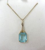 A 9ct pendant and chain set with an emerald cut blue stone.