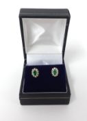 A pair of emerald and diamond cluster earrings.