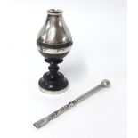 A silver incense holder with a silver bombilla on a dark wood base.