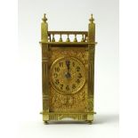 A brass carriage clock the gilt dial with embossed decoration with birds of architectural style,