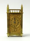 A brass carriage clock the gilt dial with embossed decoration with birds of architectural style,