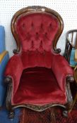 A Victorian mahogany framed upholstered and button backed armchair with carved frame.