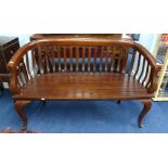 A wood framed two seater curved back bench.