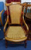 A elbow chair with cane back and seat on carved wood frame.