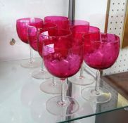 Group of eight cranberry wine glasses with etched decoration.