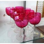 Group of eight cranberry wine glasses with etched decoration.