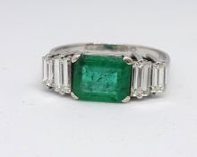 An 18ct emerald and diamond ring, set with baguette cut diamonds in a claw setting, the emerald 7.