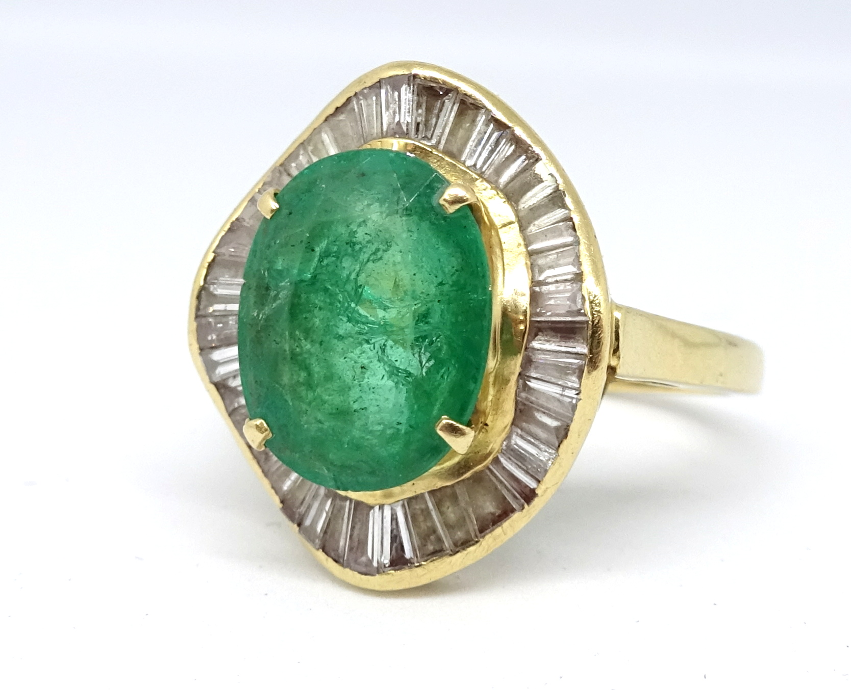 A large emerald and diamond cluster ring, the emerald approx. 11mm x 9mm set within a border of